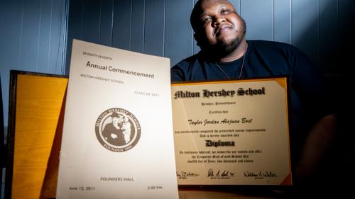Taylor Bost, 28, with his diploma and commencement program