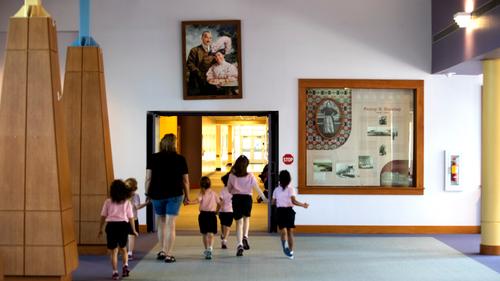 A group passes under a portrait of Milton and Catherine Hershey in Fanny Hershey Memorial Hall at the Milton Hershey School