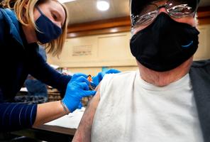 Amber Pedro, a volunteer from Family Practice Laporte, administers the vaccine into the arm of Robert Keen, 84 of Forksville, in the cafeteria of the Sullivan County Elementary School. Amber Pedro, a volunteer from Family Practice Laporte, administers the vaccine into the arm of Robert Keen, 84 of Forksville, in the cafeteria of the Sullivan County Elementary School.