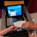 A polling judge helps guide a voter's ballot into a voting machine during the May 2022 Pennsylvania primary election.