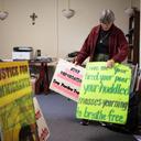 Sister Anne McCarthy with the Benedictine Sisters of Erie looks through her signs protesting President Trump’s nationwide immigration crackdown.