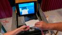 A polling judge helps guide a voter's ballot into a voting machine during the May 2022 Pennsylvania primary election.