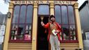 A town crier stands outside a shop.