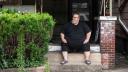 Mike Ramsey sits on the front porch of his house.