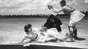 All-American Girls Professional Baseball League player Marg Callaghan sliding into home plate as umpire Norris Ward looks on.