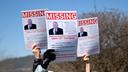 People hold up signs of U.S. Rep. Glenn Thompson that say “missing” during a protest outside his Bellefonte office.