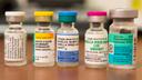 Vials containing vaccines for measles, hepatitis B, polio, and other diseases.