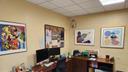 An office with four pieces of art on the walls