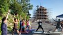 People in yoga poses in front of Reading Pagoda, which is surrounded by scaffolding. 