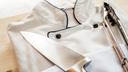 A stock image of a chef's coat and tongs on a wooden board.