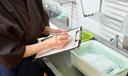 A stock image of a person with a clipboard in a kitchen.