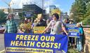 Healthcare-cost rally outside Geisinger, with participants holding signs and a banner reading “FREEZE OUR HEALTH COSTS!