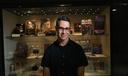 Adam Lowenstein stands in front of a display case of horror artifacts.