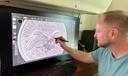 Medallic artist Eric David Custer at his workstation, showing his design for the tails side of the semiquincentennial dime on a computer screen.