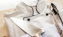 A stock image of a chef's coat and tongs on a wooden board.