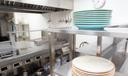 A stock image of plates stacked on a stainless steel shelf in a kitchen