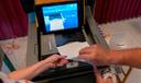 A polling judge, right, helps guide a voter's ballot into a voting machine during the Pennsylvania primary election, at Mont Alto United Methodist Church in Alto, Pa., on May 17, 2022.