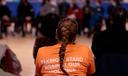 A student with long hair in a braid wears an orange T-shirt that says "taking a stand against gun violence."