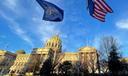 The Pennsylvania and American flags flutter in front of the Capitol building in Harrisburg.