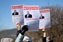 People hold up signs of U.S. Rep. Glenn Thompson that say “missing” during a protest outside his Bellefonte office.