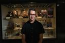 Adam Lowenstein stands in front of a display case of horror artifacts.