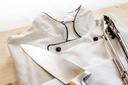 A stock image of a chef's coat and tongs on a wooden board.
