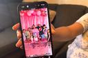 Wendys Martinez holds up her cell phone showing a photo of her husband, Carlos Moreno, and their children.