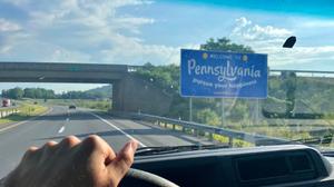 The Welcome to Pennsylvania sign can be seen over a car dashboard