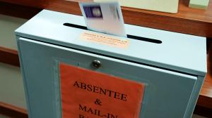 A ballot is deposited into a box at the county clerk's office in Erie. A newly approved resolution is meant to bar groups of people openly carrying firearms from gathering near polling places and drop boxes.