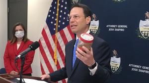 Pennsylvania Attorney General Josh Shapiro, right, holds a jar of discolored tap water during a news conference. He said the sample was from the home of a state resident whose well had been tainted by nearby natural gas drilling.