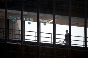 A sign that reads "HANG IN THERE WORLD" is seen in the windows of the enclosed walkway at Thomas Jefferson University Hospital in Philadelphia. State officials are asking hospitals to work together as some face a staffing crisis.
