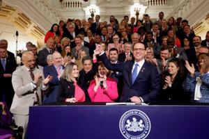 Pa. Gov. Josh Shapiro holds up Senate President Pro Tempore Kim Ward's hand as he signs the first bill of his tenure.