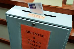 A ballot is deposited into a box at the county clerk's office in Erie. A newly approved resolution is meant to bar groups of people openly carrying firearms from gathering near polling places and drop boxes.