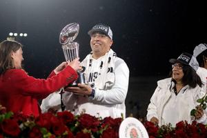 Penn State head football coach James Franklin is presented with the Rose Bowl trophy as President Bendapudi looks on.
