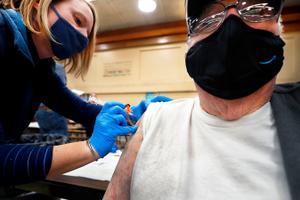 Amber Pedro, a volunteer from Family Practice Laporte, administers the vaccine into the arm of Robert Keen, 84 of Forksville, in the cafeteria of the Sullivan County Elementary School.
