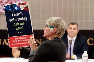 A woman shows Pennsylvania House Speaker Mark Rozzi a sign advocating for the state to open its primaries to unaffiliated voters during a listening tour stop in Philadelphia.
