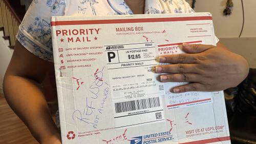 Wendys Martinez holds up the package containing her husband's replacement cane and hearing aids that she tried to send to him in ICE detention at Cambria County Prison.