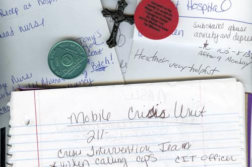 A photo of a notebook, paper, a cross, and sobriety chips.