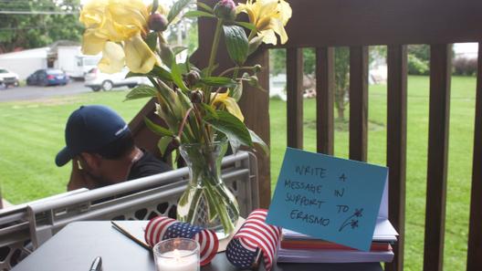 Flowers and a small American flag on a table at a vigil in Muhlenberg Township, where supporters were invited to write messages to Erasmo Zavala. He is being held at Moshannon Valley Processing Center.