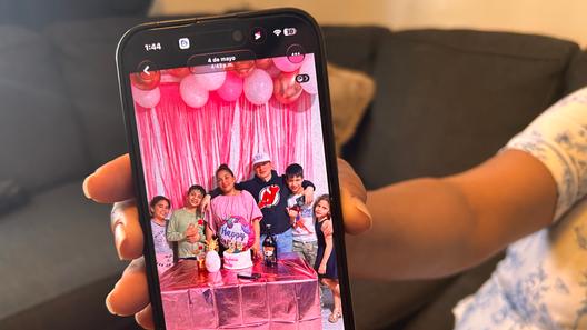 Wendys Martinez holds up her cell phone showing a photo of her husband, Carlos Moreno, and their children.