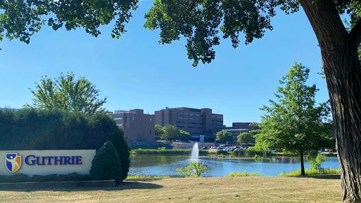 A health system campus framed by trees with a sign that says “Guthrie.” A health system campus framed by trees with a sign that says “Guthrie.”