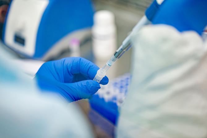 A syringe is inserted into a vial.