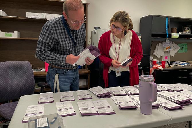Election clerk Tony Phillips and election intern Maggie Bachman sort the mail ballots received on Election Day into precincts.