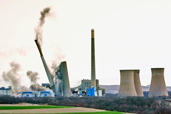 The smokestacks of the former coal-fired Homer City Generating Station crumble in a planned demolition in Homer City, Pa.