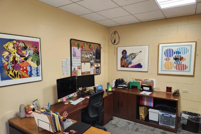 An office with four pieces of art on the walls