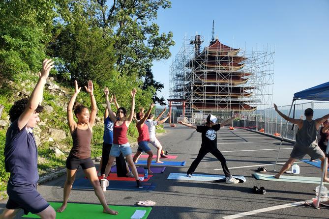 People in yoga poses in front of Reading Pagoda, which is surrounded by scaffolding. 