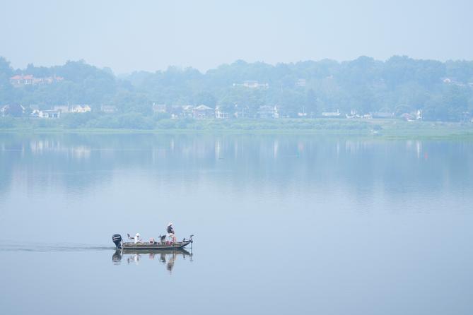 People fish on the Susquehanna River amidst haze from Canadian wildfires, June 29, 2023, in Harrisburg, Pa.