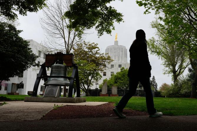 A person walks by a Liberty Bell replica at the Oregon state Capitol on Tuesday, April 14, 2026, in Salem, Ore.