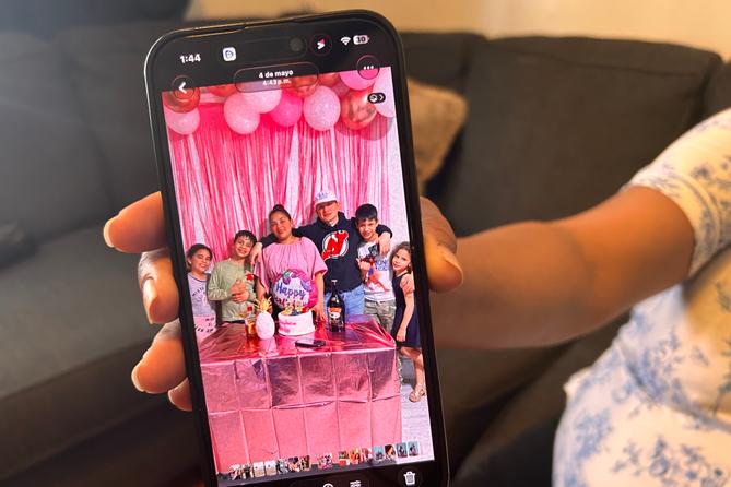 Wendys Martinez holds up her cell phone showing a photo of her husband, Carlos Moreno, and their children. Wendys Martinez holds up her cell phone showing a photo of her husband, Carlos Moreno, and their children.