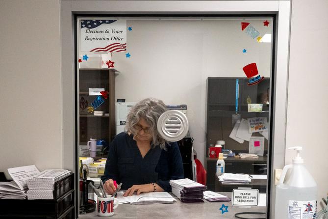 Stacy Guyer uses a pink highlighter to mark off the names corresponding to the mail ballot request list as she verifies the ballots that have been scanned in.